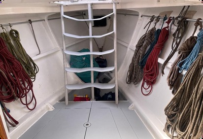 Sail locker with white ladder and coiled lines on both sides